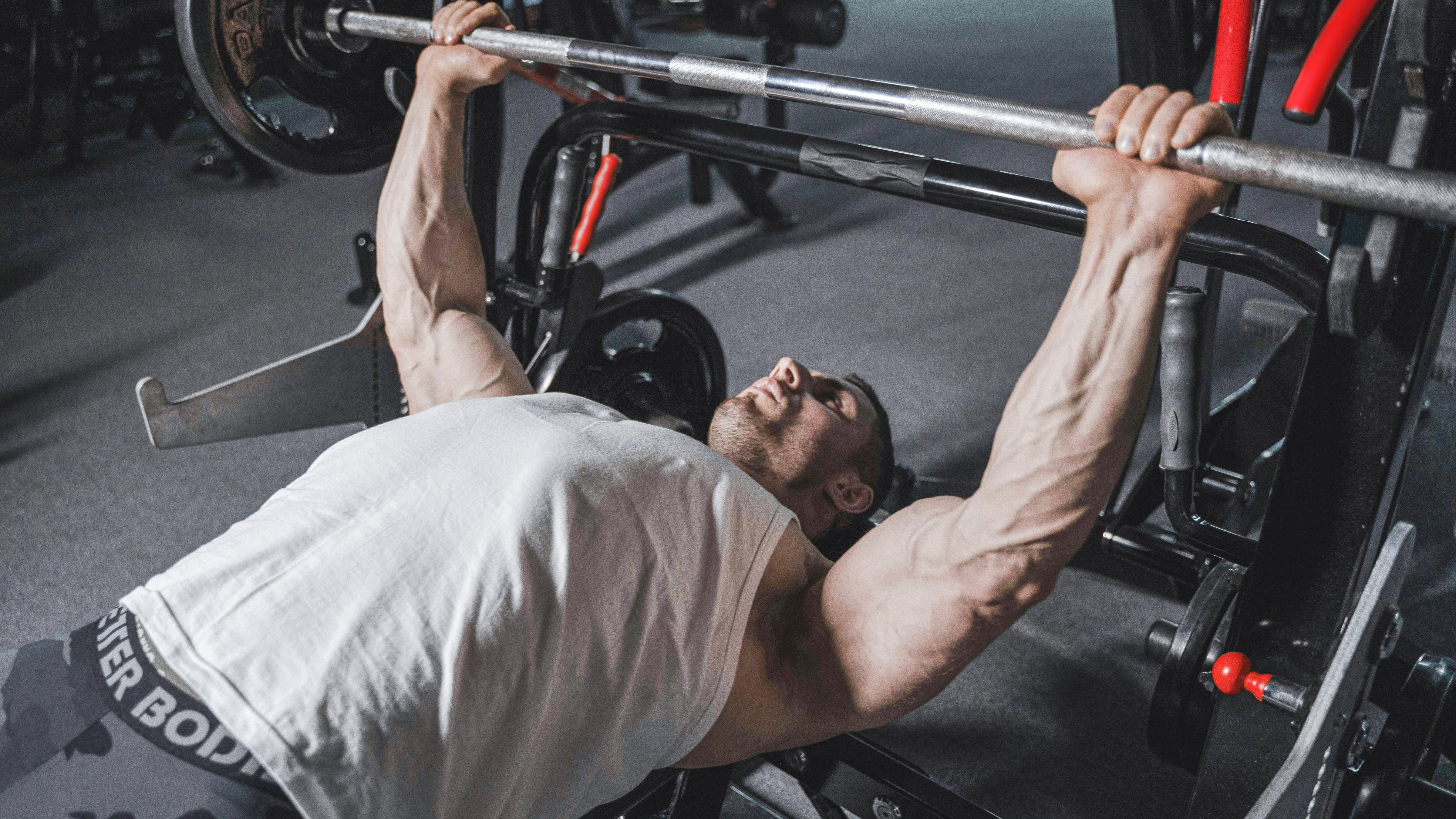 Man performing bench press in gym, emphasizing strength training for healthy aging.