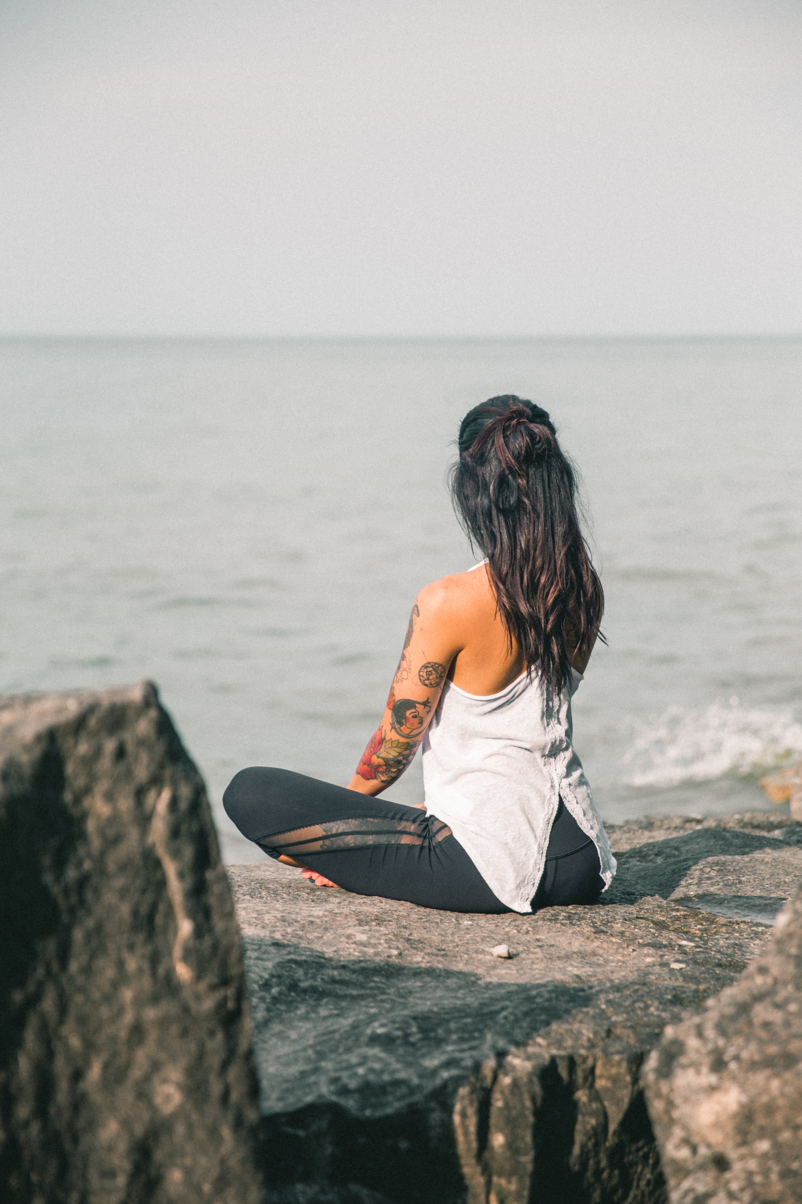 Woman practicing breathing and yoga by the sea for Longevity Plus wellness