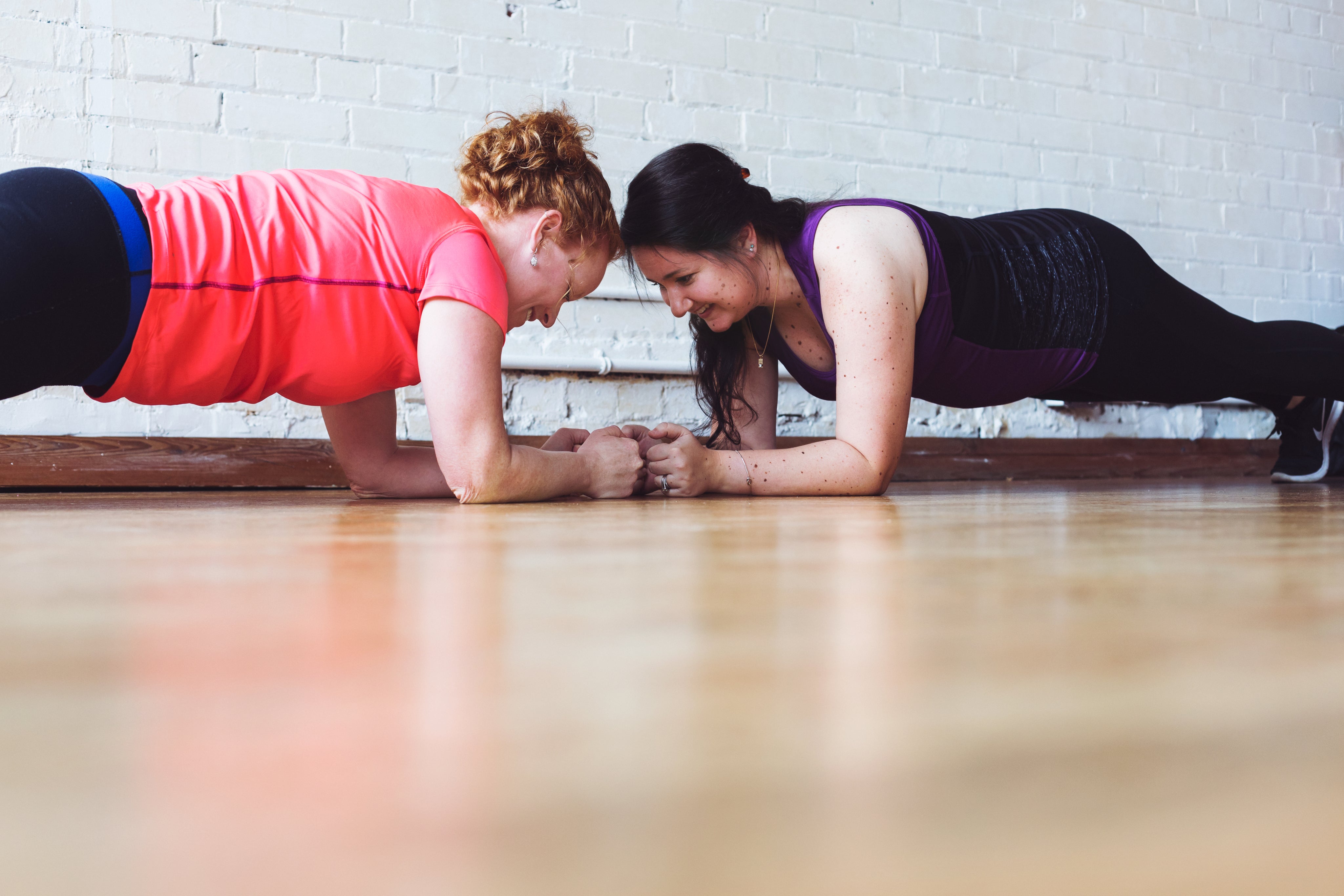 Two women doing plank exercises for Longevity Plus fitness and wellness
